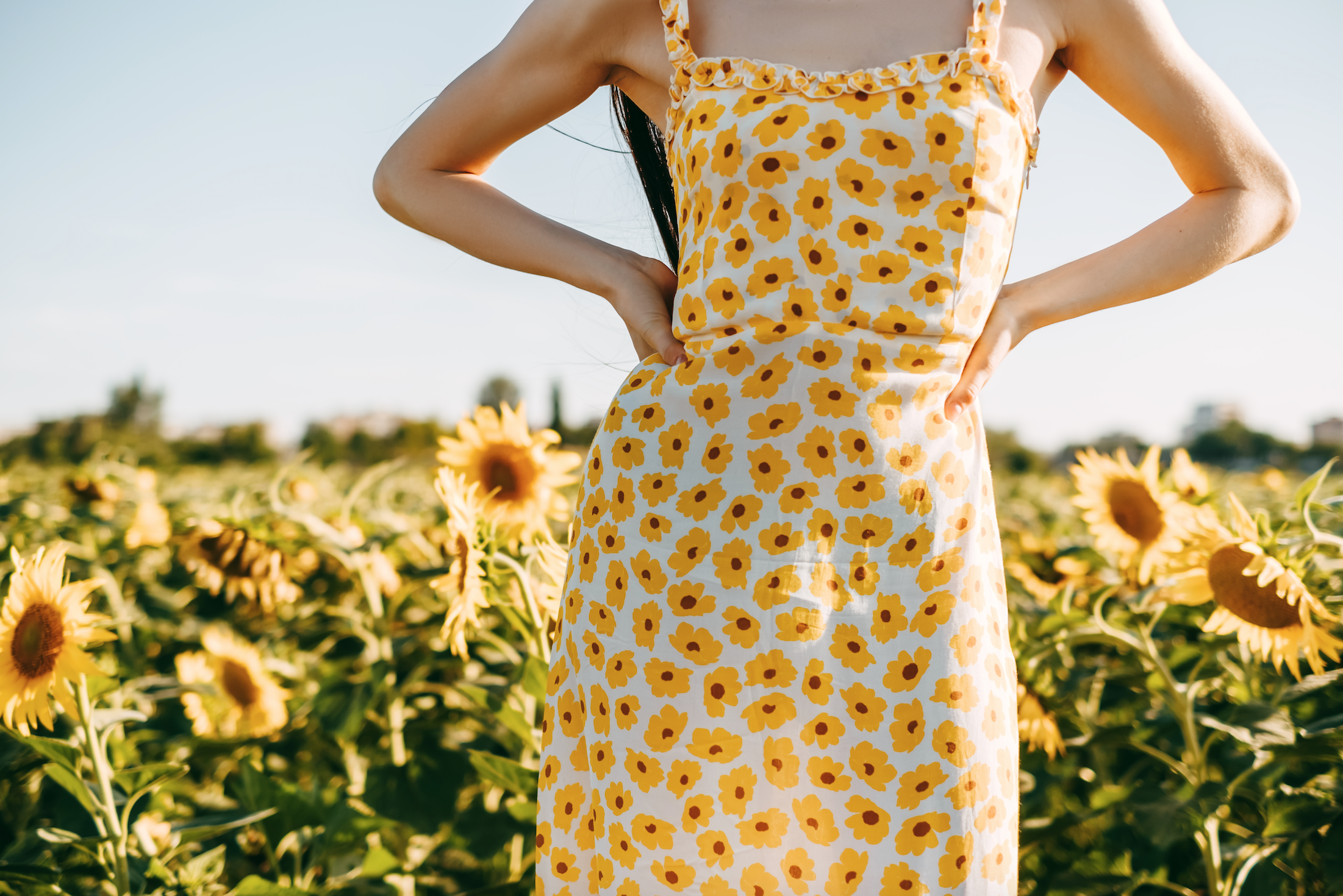 Young caucasian woman in sunflower dress standing in...